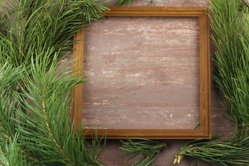 green fir branches and wooden frame top view shabby brown background copy space