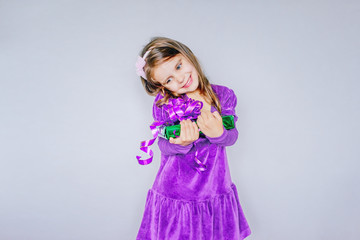 Merry Christmas! . Little girl holding a gift on a gray isolate background. concept of Christmas gifts.