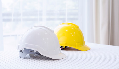 Helmet placed on a white table, White and  yellow hard safety helmet hat for safety project of...