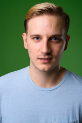Fototapeta premium Young handsome man with blond hair against green background