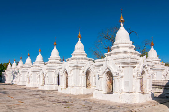 Kuthodaw Pagoda contains the worlds biggest book. There are 729 white stupas with caves with a marble slab inside page with buddhist inscription. Mandalay, Myanmar.