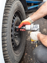 technician attaches car wheel by pneumatic wrench