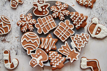 Fresh and tasty Christmas gingerbread cookies placed on white rusty table. Different shapes. Santa claus, snowflake, tree, gift, snowman.