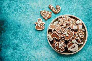 Rustical plate filled with delicous, varous Christmas shaped gingerbread cookies. Top view. Placed on blue rustic background.