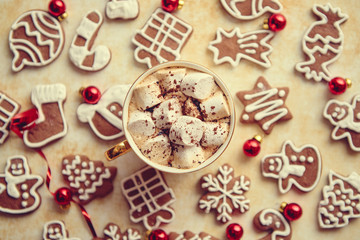 Cup of hot chocolate with tasety marshmellows. Fresh baked Christmas shaped gingerbread cookies on sides. With Xmas decorations. View from above.