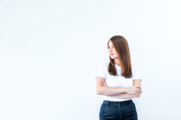 Portrait of smiling confident young caucasian woman standing with crossed or folded arms and looking away at copy space isolated over white background. Selective focus, copy space.