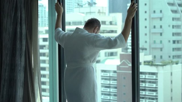 Sad man leaning on the window and thinking about his problems