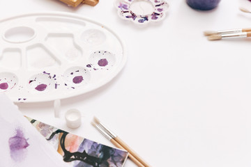 Drawing tools, stationary supplies, workplace of artist. Watercolor paints on white background.