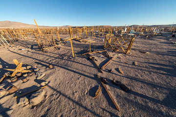Fototapeta premium Amazing view over an old and abandoned saltpeter people cemetery inside the awesome Atacama Desert, loneliness to rest in peace in a remote location during the sunset hour. Taltal, Chile 