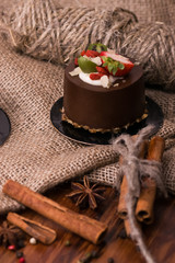 Cake with fruit on a wooden table and burlap. Dessert with berries, cinnamon and nuts