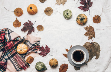 Autumn cozy composition. Warm scarf, hot tea, dried leaves on white background. Top view, copy space