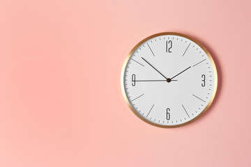 Stylish analog clock hanging on color wall. Space for text
