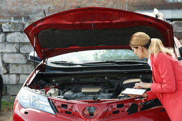 Insurance agent with tablet inspecting broken car after accident