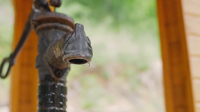 Water tap, outdoors in the nature, representing shortage of water. Water stand in the countryside. Water droplets drip into the standpipe.