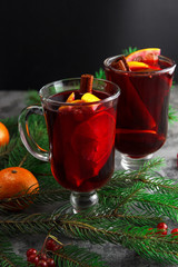 Mulled wine in glasses. Citrus fruits and cinnamon sticks. Christmas decor made of fir branches. Christmas lights