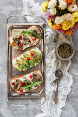 Light sandwiches with vegetables, pumpkin seeds and arugula on a gray background. Vintage tray. Serving food. Flat lay.