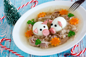 Jellied meat kholodets, meat aspic decorated with boiled eggs shaped funny pigs, carrot flowers and...