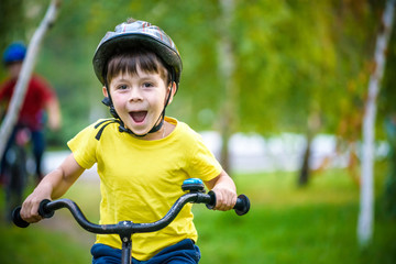 Fototapeta na wymiar Happy kid boy of 6 years having fun in autumn forest with a bicycle on beautiful fall day. Active child making sports. Safety, sports, leisure with kids concept