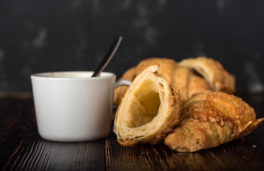 Cup of coffee with croissants on a wooden table