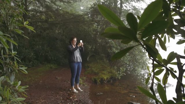 Woman Hiking and Taking Picture of Misty Lake in Nature