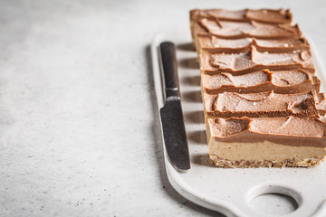 Raw vegan chocolate cashew cake on a light background, copy space.
