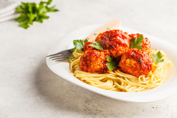 Pasta with chicken meatballs in tomato sauce in a white plate, copy space.