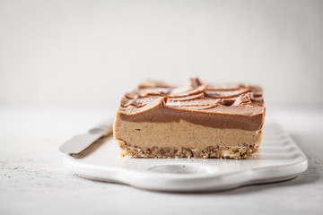 Raw vegan chocolate cashew cake on a light background, copy space.
