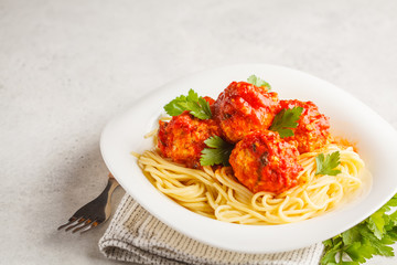 Pasta with chicken meatballs in tomato sauce in a white plate, copy space.