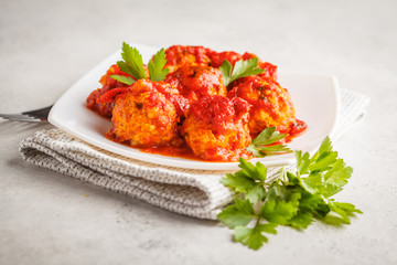 Chicken meatballs with tomato sauce in a white plate.