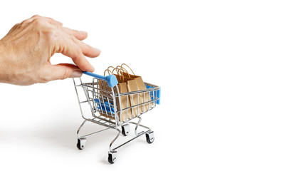 Female hand gently holding a toy supermarket trolley with paper shopping bags. Isolated on white....