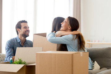 Happy mother embrace small daughter family sitting on sofa in living room with heap of cardboard boxes at new home. Relocation and moving or remodeling, buy or rent new house mortgage and loan concept