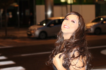 Stylish trans woman smiling outdoors at night 