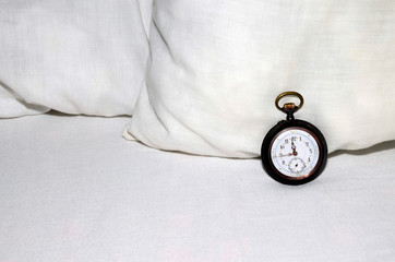pocket watch on pillow and bed