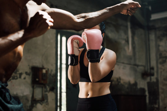 Strong brunette woman boxing indoors with her coach.