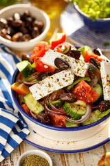 Greek salad. Traditional Greek salad consisting of fresh vegetables such as tomatoes, cucumbers, peppers, onions, oregano and olive oil, top view. Delicious vegetarian, mediterranean dish