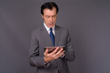 Portrait of mature handsome businessman using digital tablet