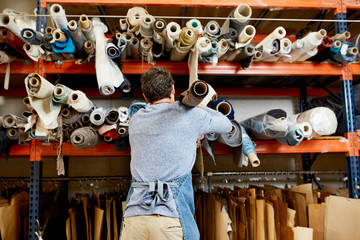 Worker Removing Rolled Up Fabric From Shelf At Sofa Workshop