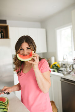 Naklejki Woman having fun with watermelon shapes in kitchen