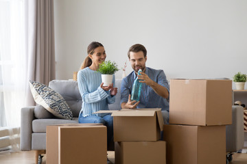 Married diverse couple sitting together on sofa in living room at new modern home unpack belongings...