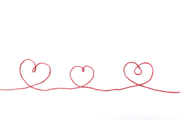 Red thread and three hearts isolated on white background