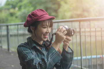 pretty cool young Asian woman with retro film camera or mirrorless camera in modern garden park