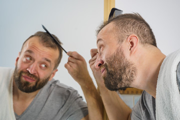 Obraz premium Man using comb in bathroom