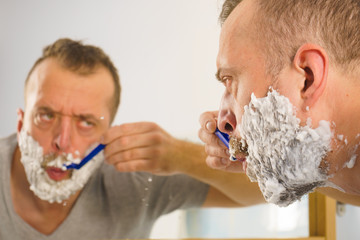 Guy shaving his beard in bathroom