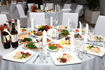 cheerful wedding celebration with a beautiful festive table, treats, champagne glasses, candles, flowers in the restaurant with a magnificent decor