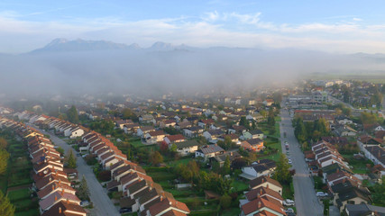 AERIAL: Dense morning mist gathers over the suburban neighborhood in Slovenia.