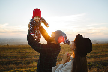 The dad holds his face in his arms with his mother. Photo session with family at sunset.