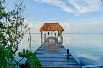 A couple on hammocks in a palapa over the water at Caribbean