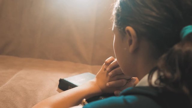 Little girl praying in the night. Little girl hand praying lifestyle . little girl holy bible prays with bible in her hands. the catholicism sacred holy bible. children and religion upbringing faith