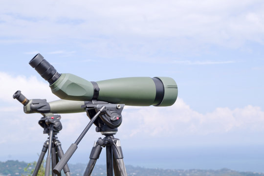 Green spotting scope or monocular at mountain top against the background of a mountain landscape in summer day. Observation of birds, birdwatching