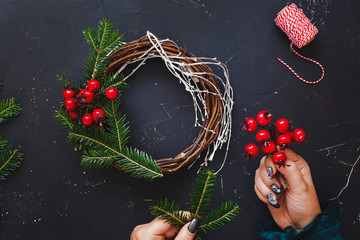 Rustic Christmas grapevine wreath. Female hands make Christmas wreath with natural spruce branches....
